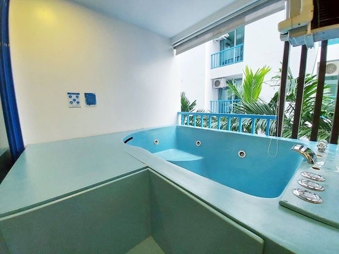 Un baño moderno con una bañera grande, ducha y lavamanos. Hay dos ventanas que ofrecen luz natural y vistas al exterior.