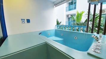 Un baño moderno con una bañera grande, ducha y lavamanos. Hay dos ventanas que ofrecen luz natural y vistas al exterior.