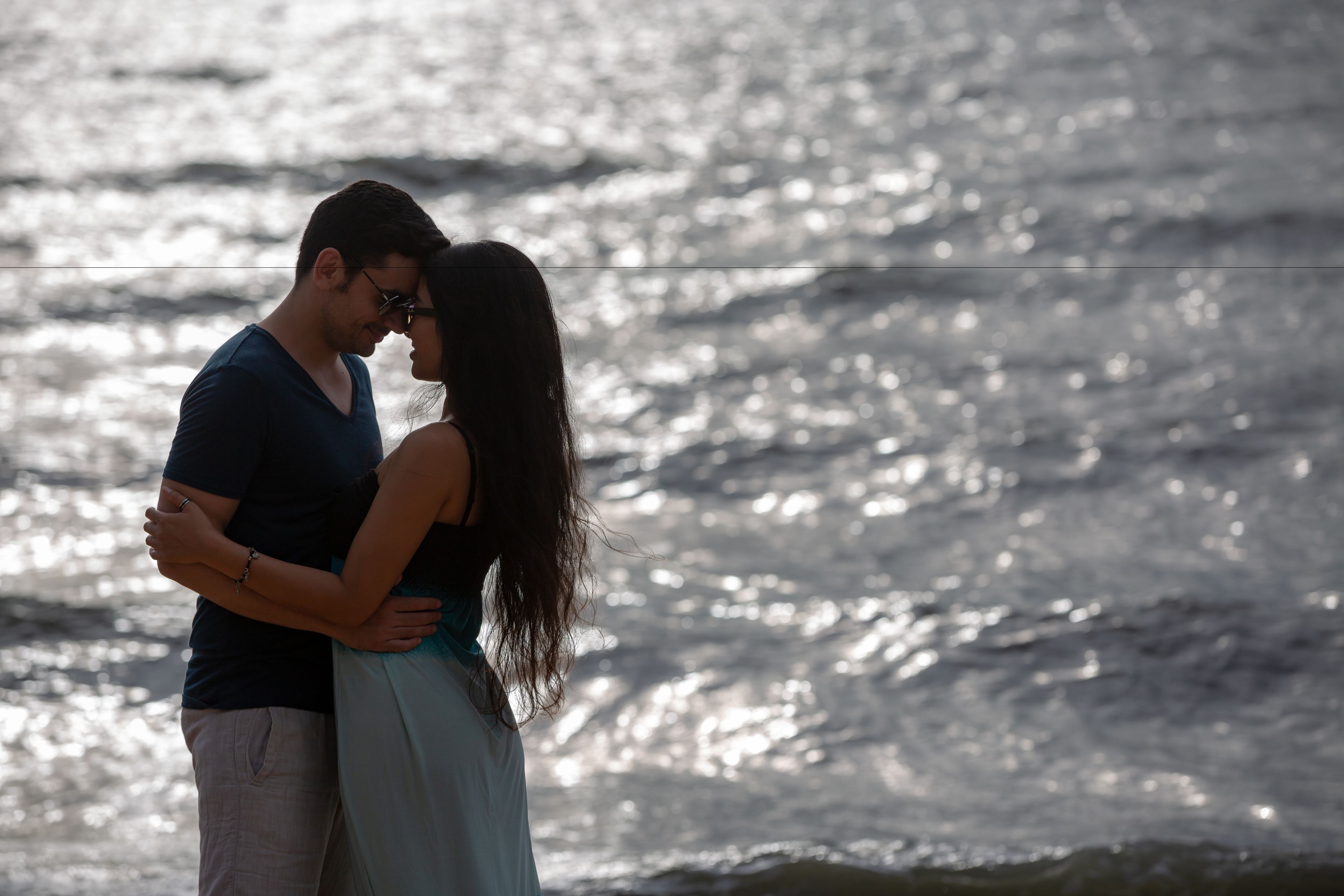 A couple embracing by a body of water.