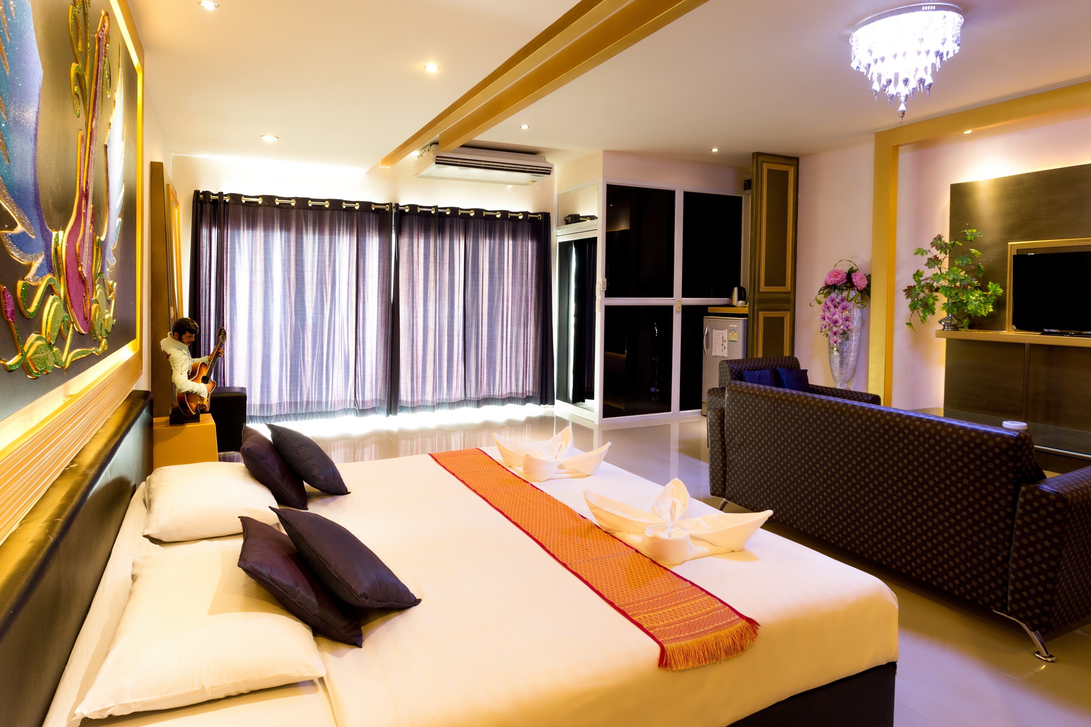A hotel room with a large bed, a TV, a desk, and a window with curtains.