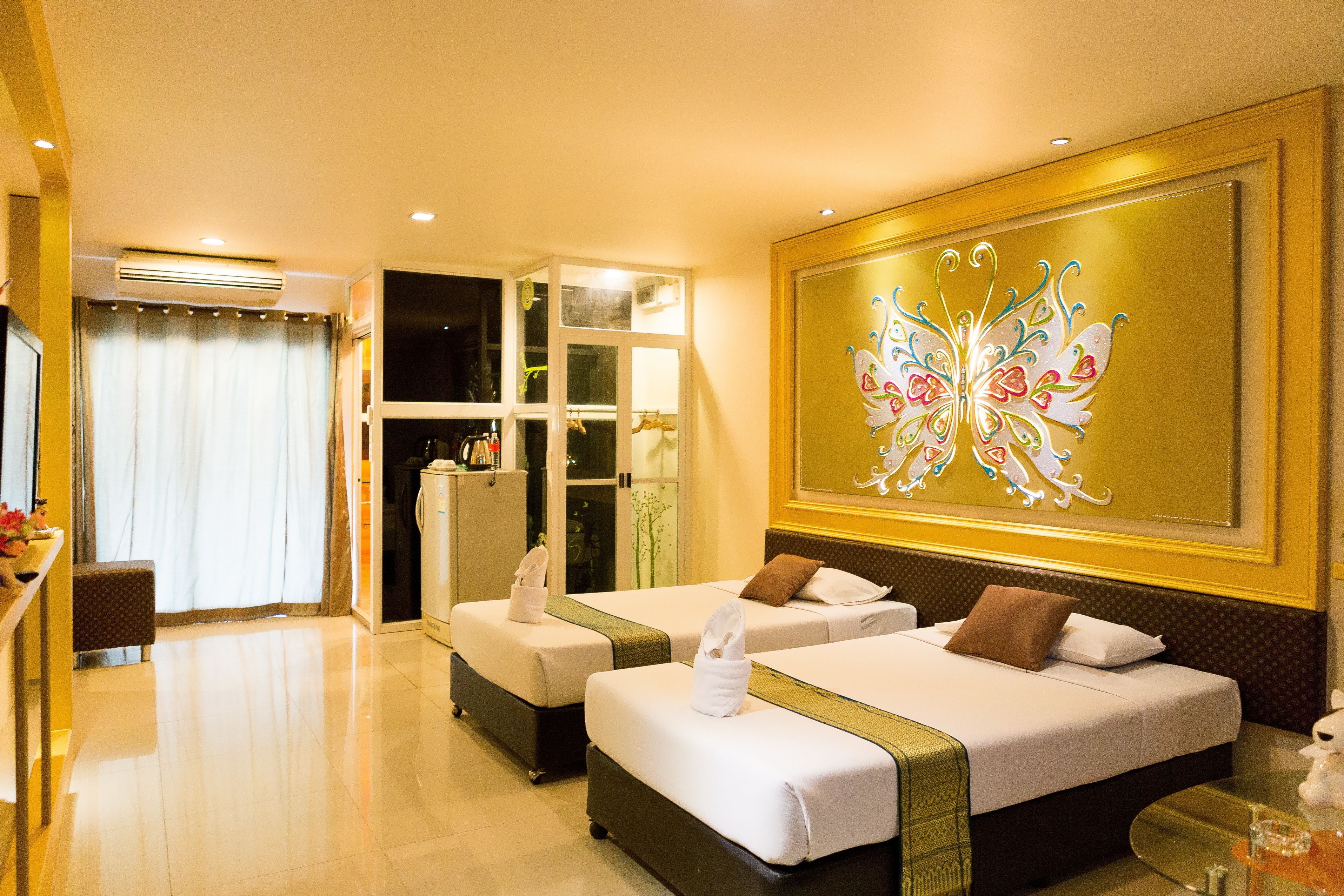 A hotel room with two beds, a large butterfly mural, and a view of the outside.