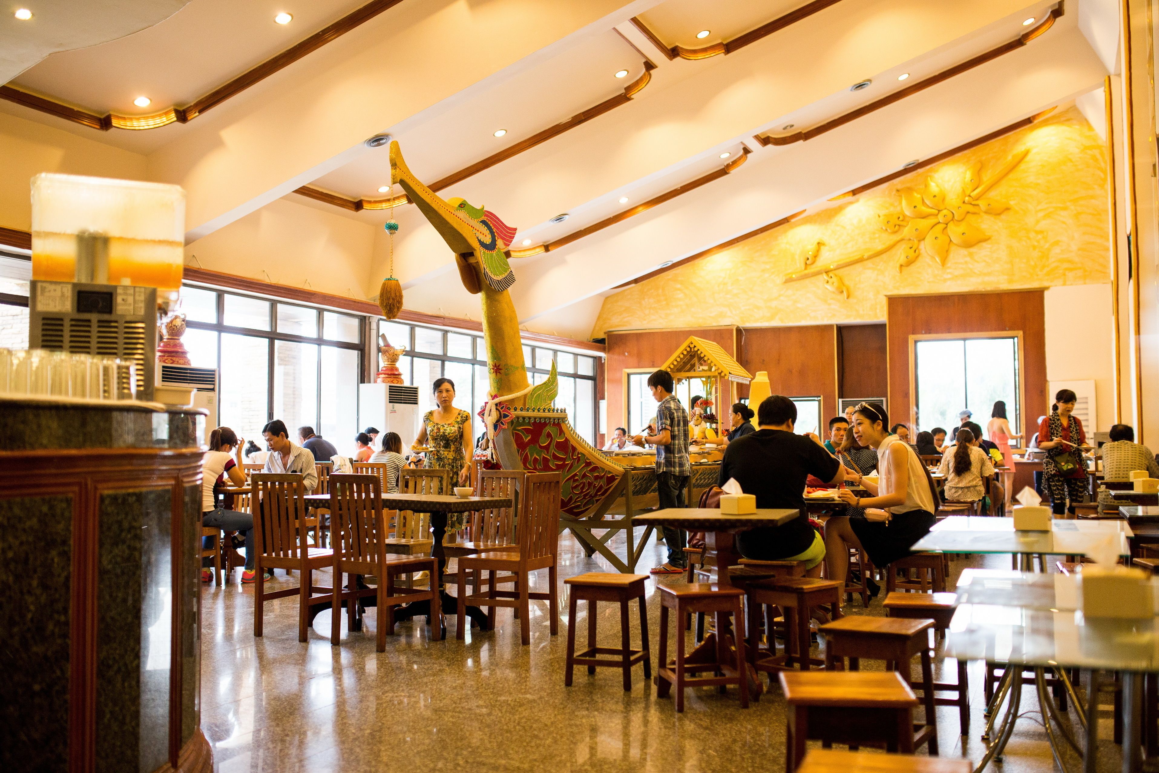 Ein Restaurant mit Holztischen und einer verzierten Decke.