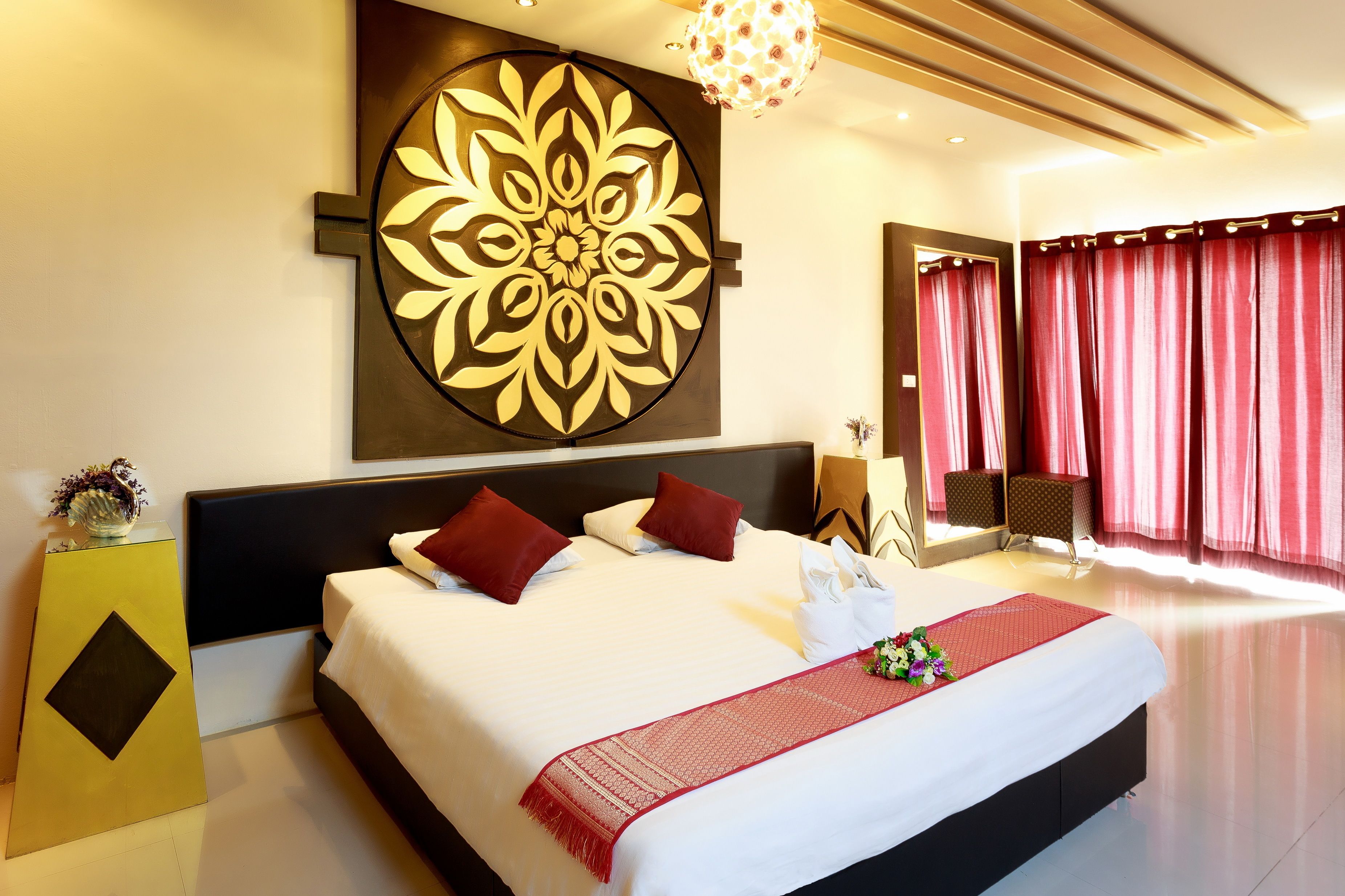 Une chambre d’hôtel moderne avec un grand lit, un élément décoratif mural et un rideau rouge.