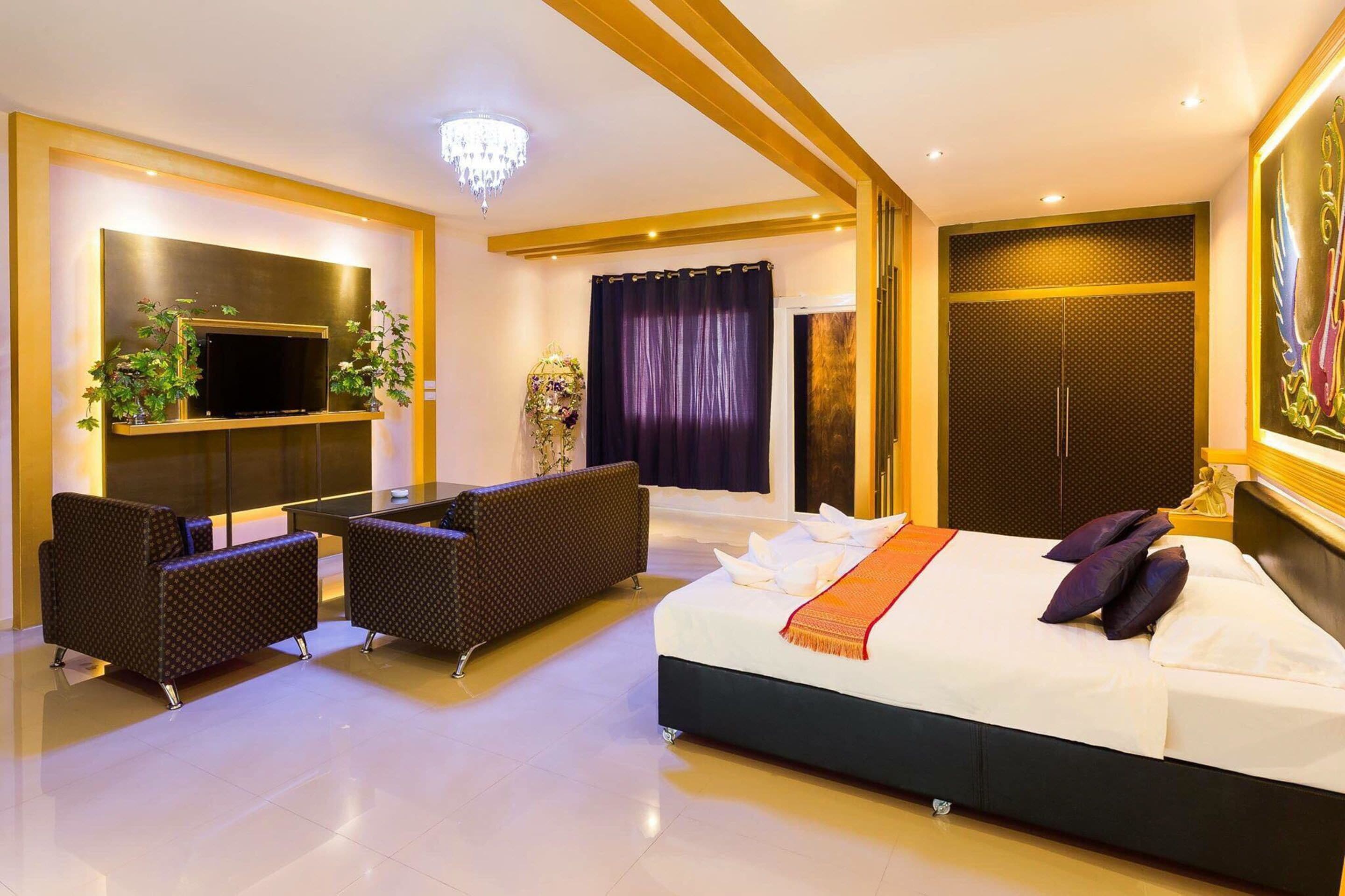 Una habitación de hotel moderna con una cama grande, un televisor montado en la pared, un área de descanso con dos sofás y una araña.