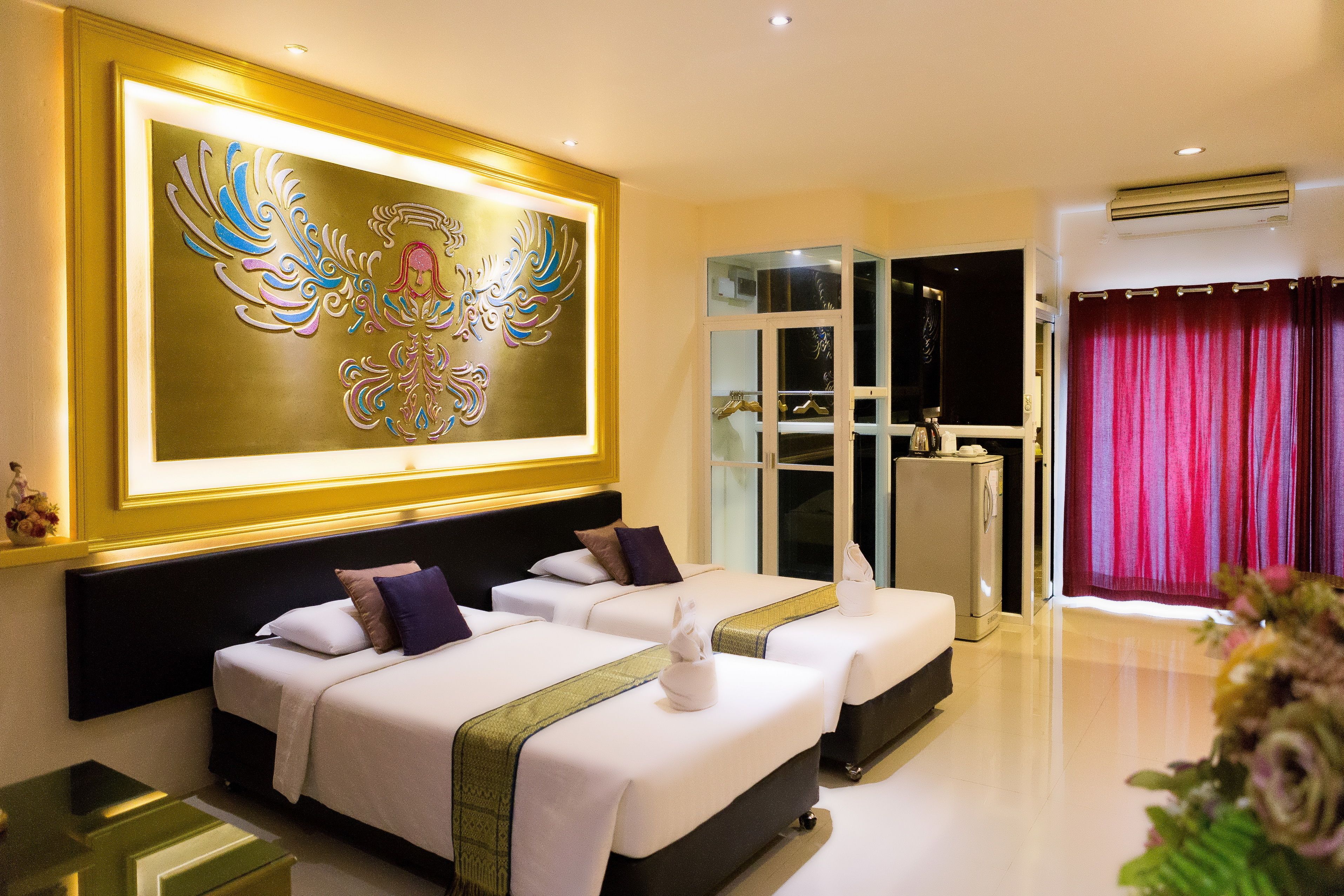 A hotel room with two beds, a large decorative wall piece, a window with curtains, and a small table.