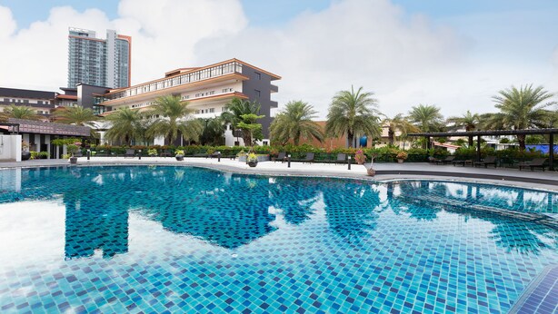 A swimming pool with blue tiles, surrounded by palm trees and modern buildings. - Marble Garden View Pattaya (Pattaya)
