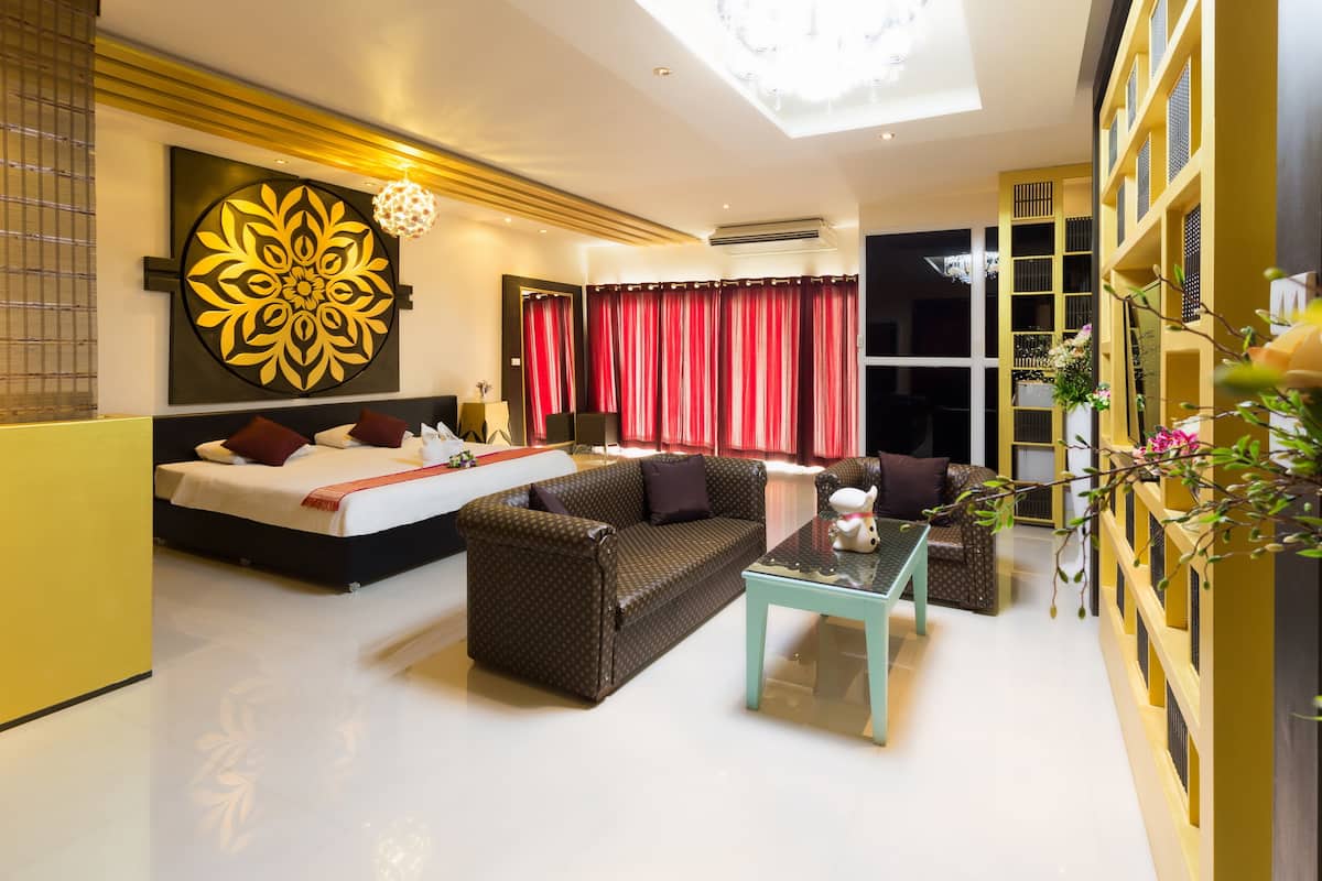 A modern hotel room with a bed, sofa, and a glass coffee table.