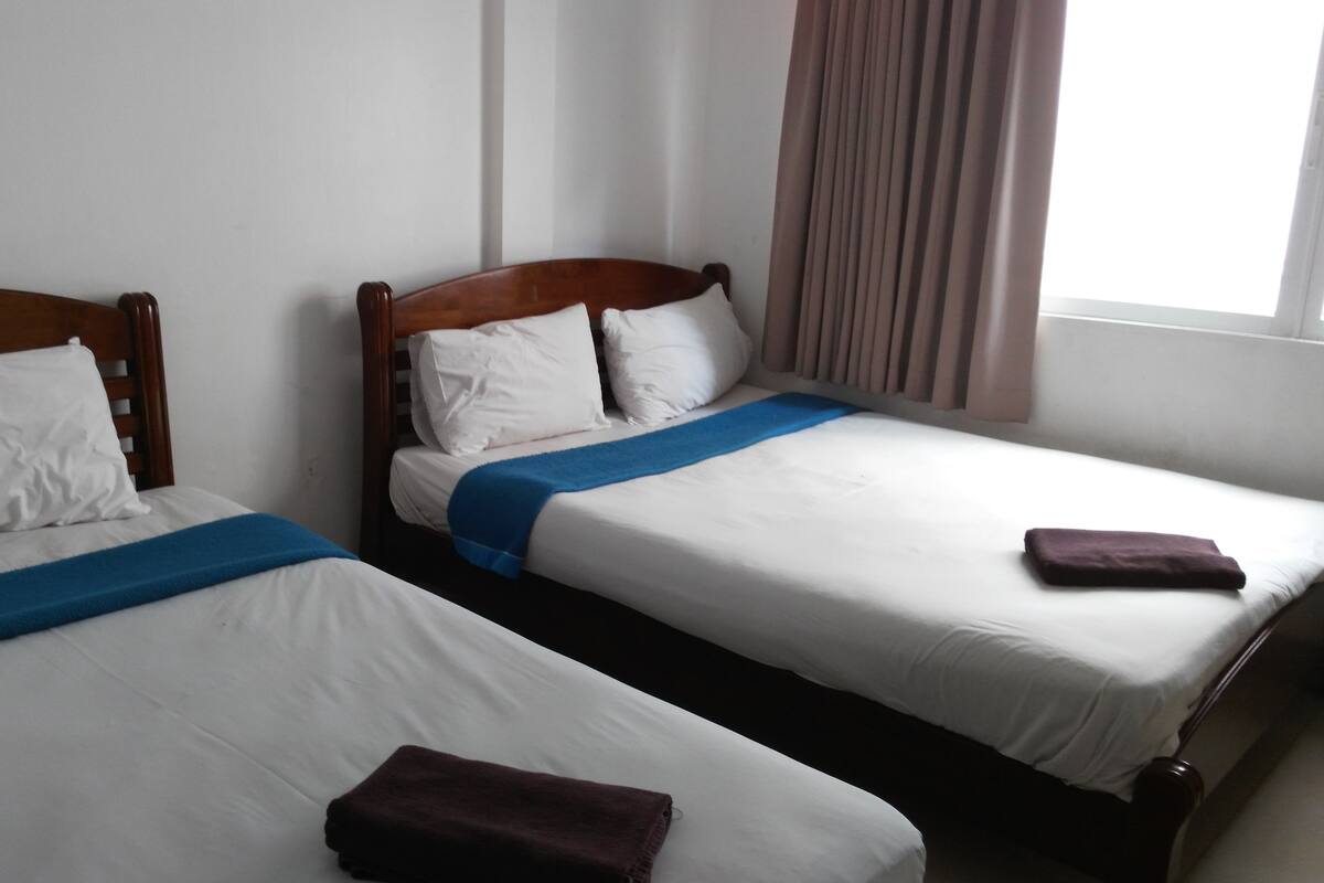 Two single beds with wooden headboards, white bedding, and blue and brown towels.