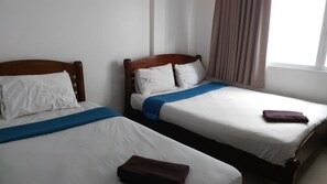 Two single beds with wooden headboards, white bedding, and blue and brown towels. - Al-Sana Hotel (Bangkok)