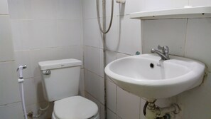 A small bathroom with a white toilet, a white sink, and a shower head. - Al-Sana Hotel (Bangkok)