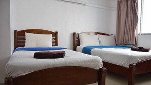 Two wooden beds with white linens and blue blankets, a brown pillow on the left bed, and a brown bag on the right bed. - Al-Sana Hotel (Bangkok)