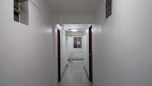 A narrow, white-walled hallway with a tiled floor leading to a door at the end. - Al-Sana Hotel (Bangkok)