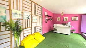 Una habitación con piso de césped artificial verde, una recepción y una pared rosa con cuadros enmarcados.