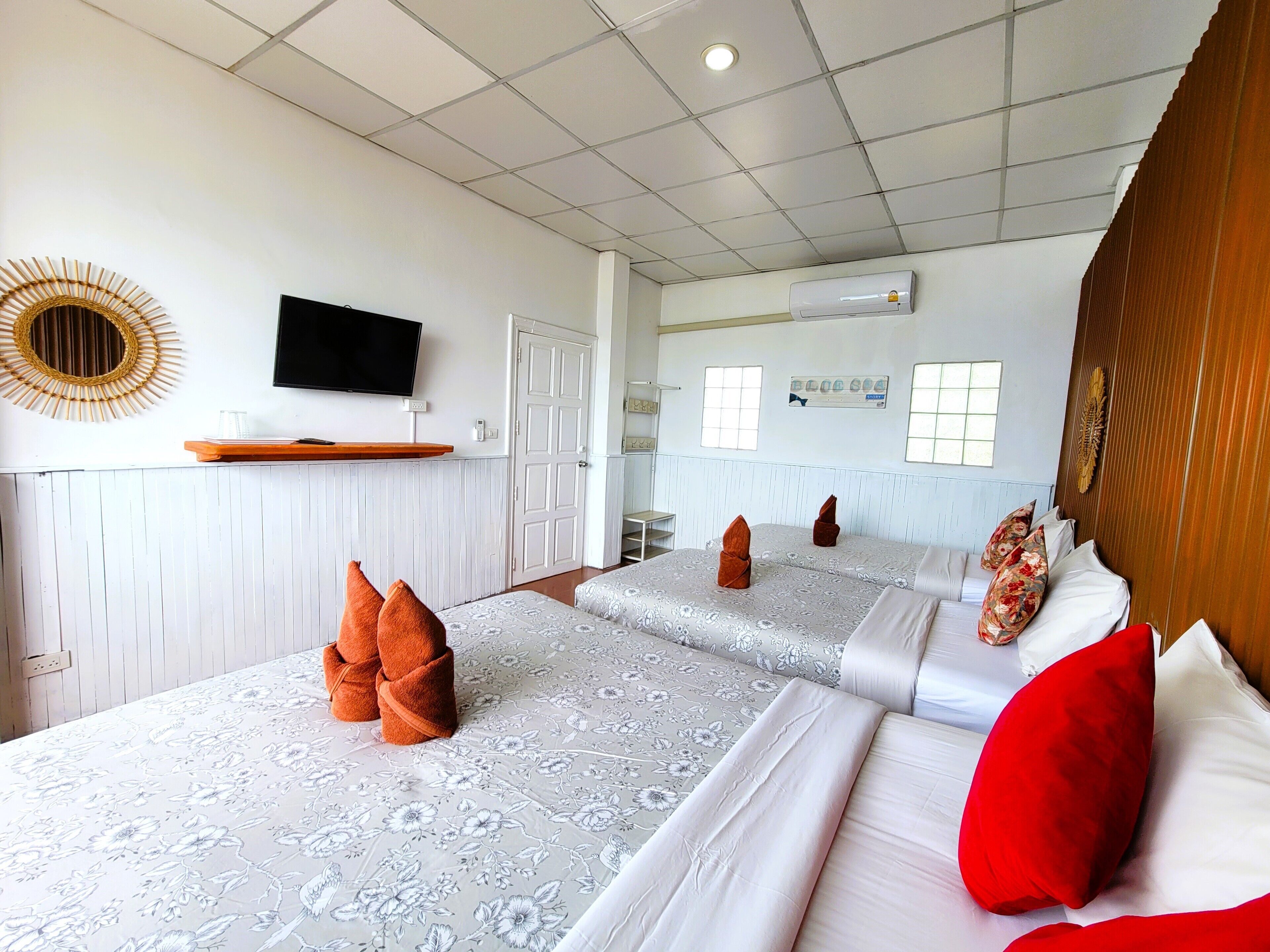 A hotel room with two beds, a television, a mirror, and a window.