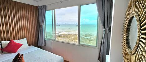 Un dormitorio con cama, vista al mar y un espejo decorativo.