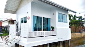 Una casa flotante blanca con balcón, ventanas amplias y un flotador en la pared.