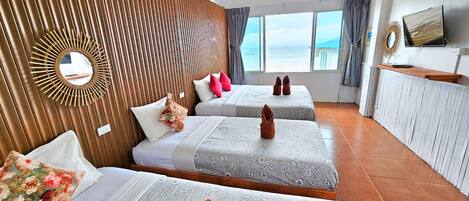A hotel room with two beds, a wooden wall panel, a large window with a view, a mirror, and a TV on the wall.
