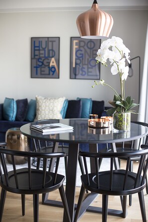 A modern dining area with a glass table, black chairs, a copper pendant light, and a white orchid in a vase. - Frogner House - Vika (Oslo)