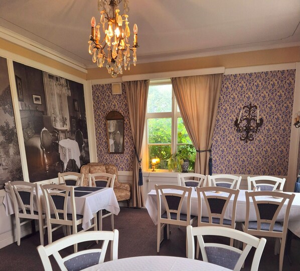 Comedor con candelabro, papel tapiz estampado y vistas a la vegetación.