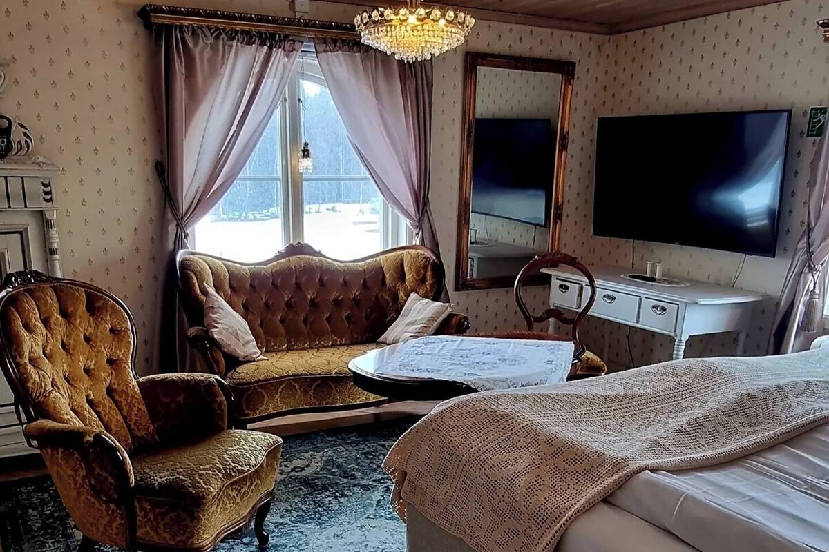 Una habitación con cama, sofá, sillón, escritorio y televisor.