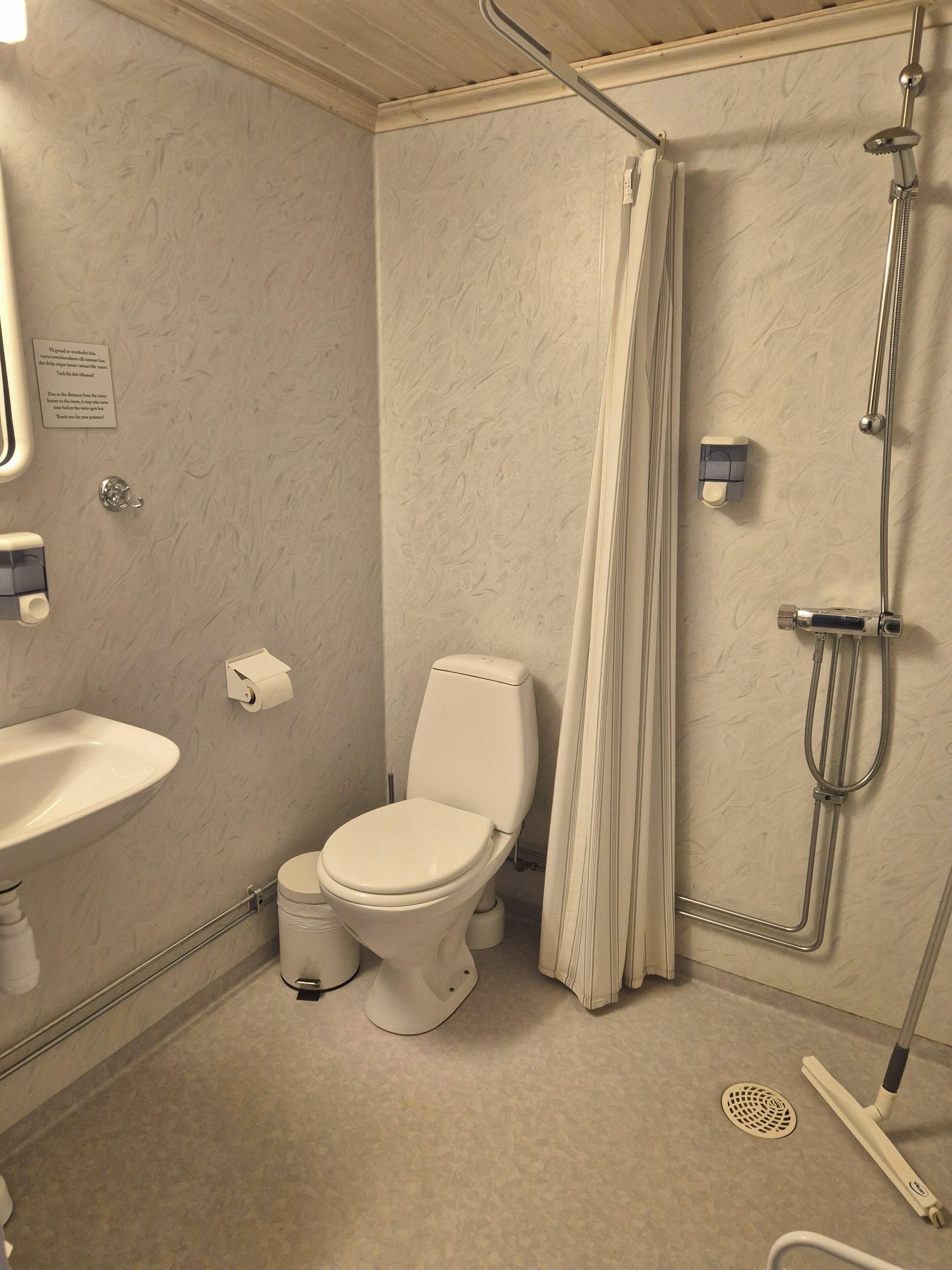 Ein Badezimmer mit Toilette, Waschbecken, Dusche und einem Handtrockner.