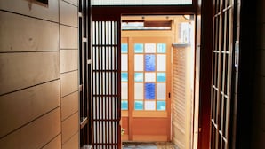 Un pasillo con paneles de madera, una puerta de madera con paneles de vidrio y una lámpara colgante.