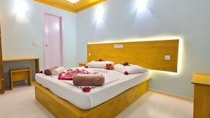 A bedroom with a bed, bedside tables, a wooden wardrobe, and a door.
