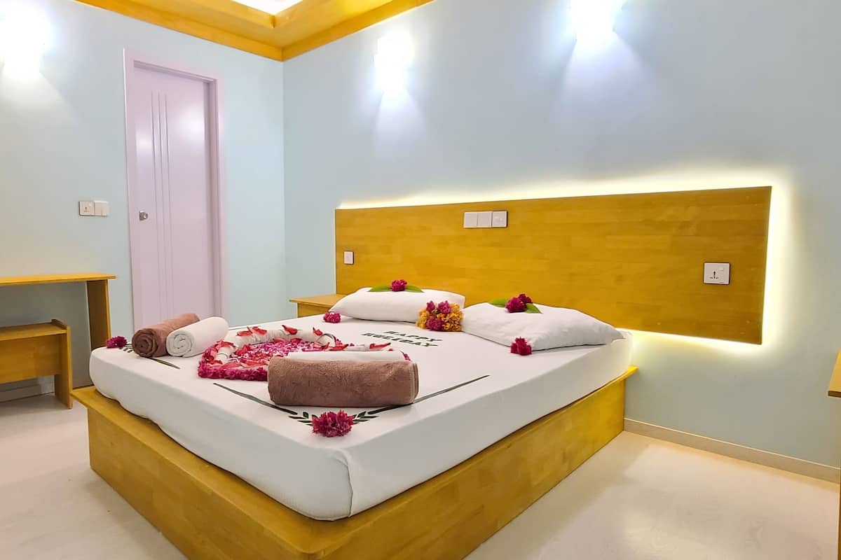 Un dormitorio con cama, mesitas de noche, un armario de madera y una puerta.