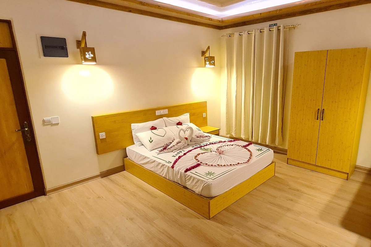 Una habitación de hotel con una cama de madera, un armario, un escritorio y un televisor.