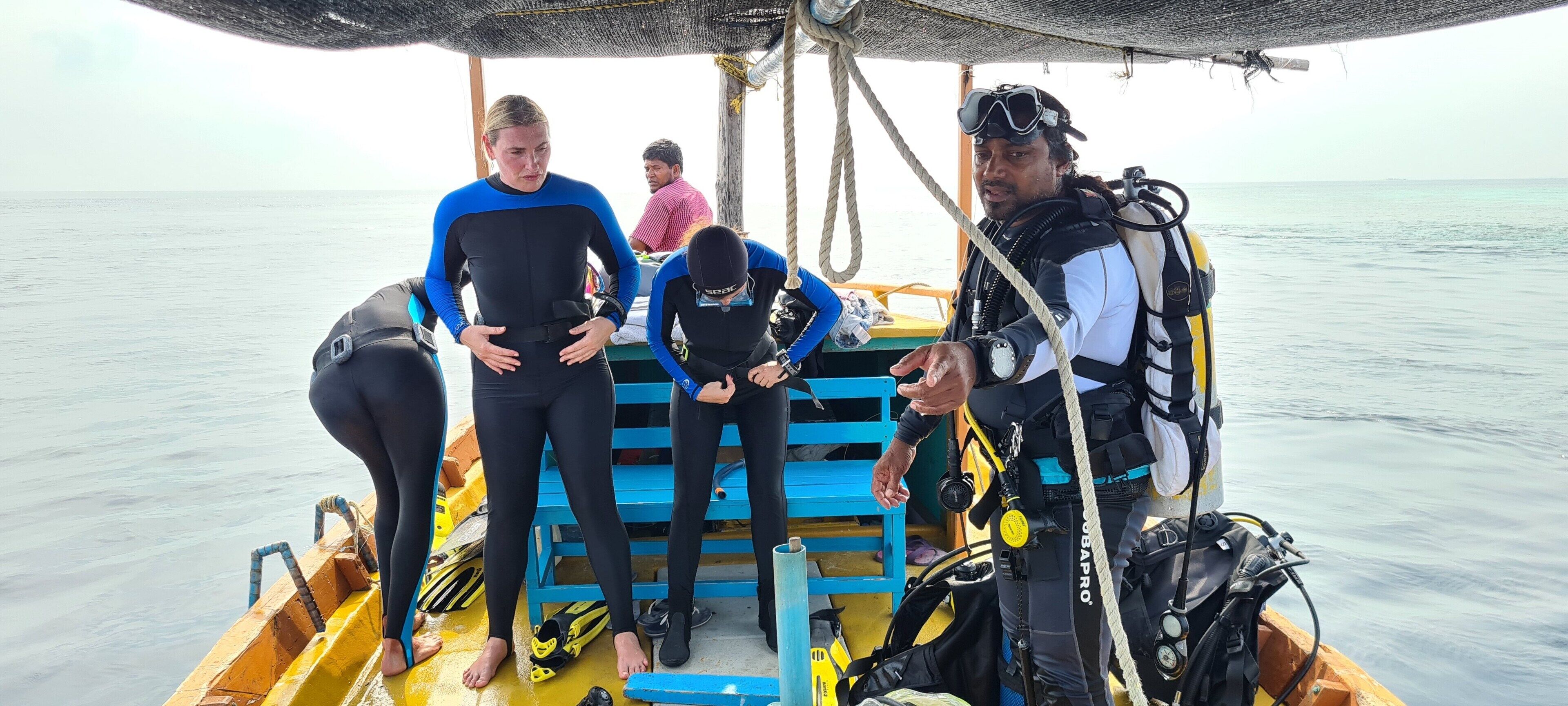 A group of people on a boat with diving equipment, including a wetsuit and a scuba tank.