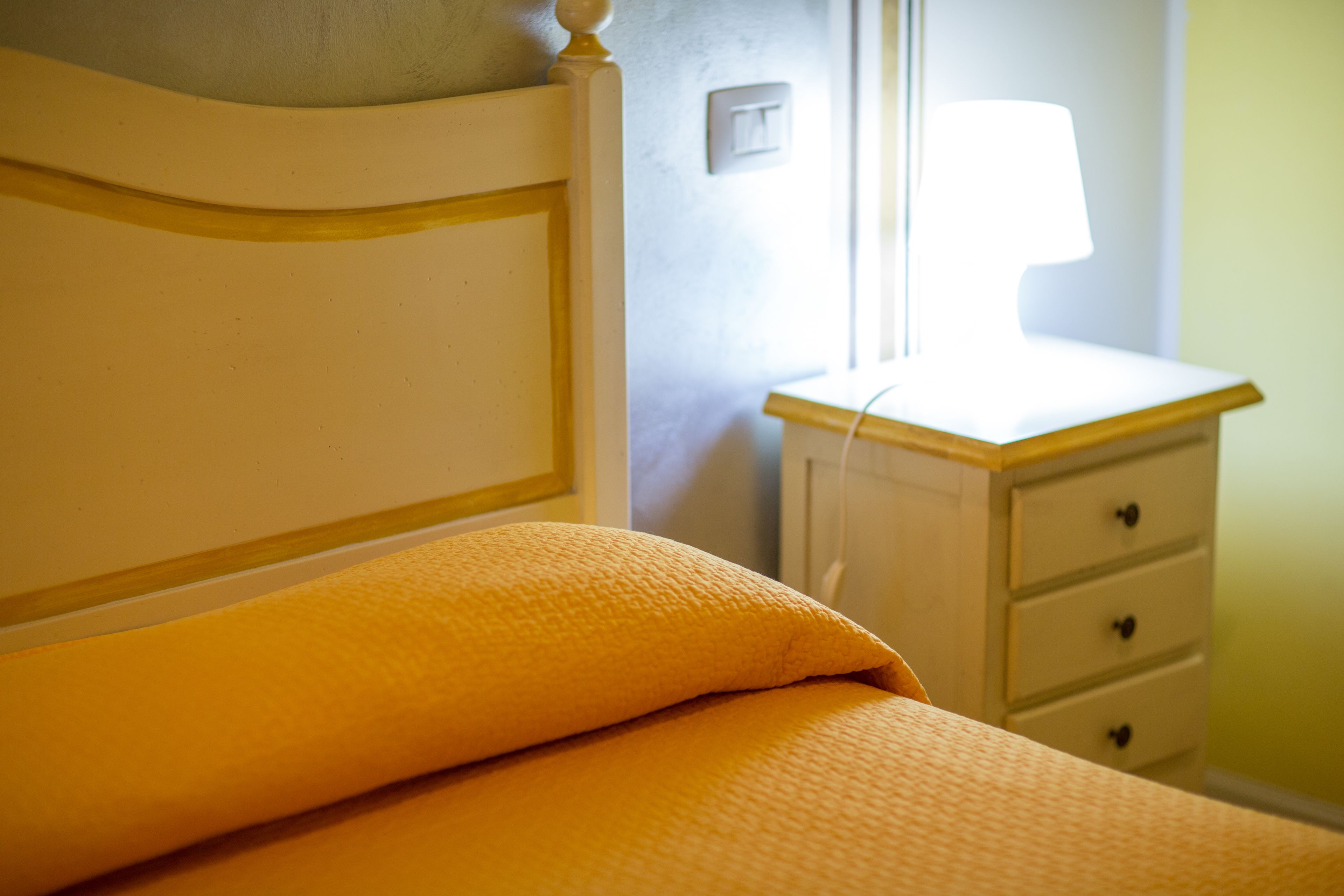 A bedroom with a bed, a nightstand, and a lamp.