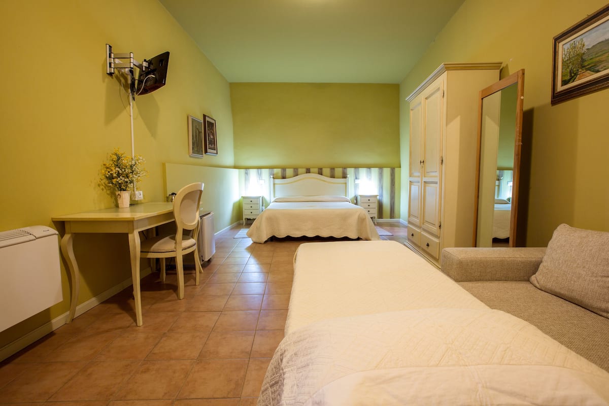 A bedroom with a bed, a desk, a chair, a wardrobe, and a radiator.