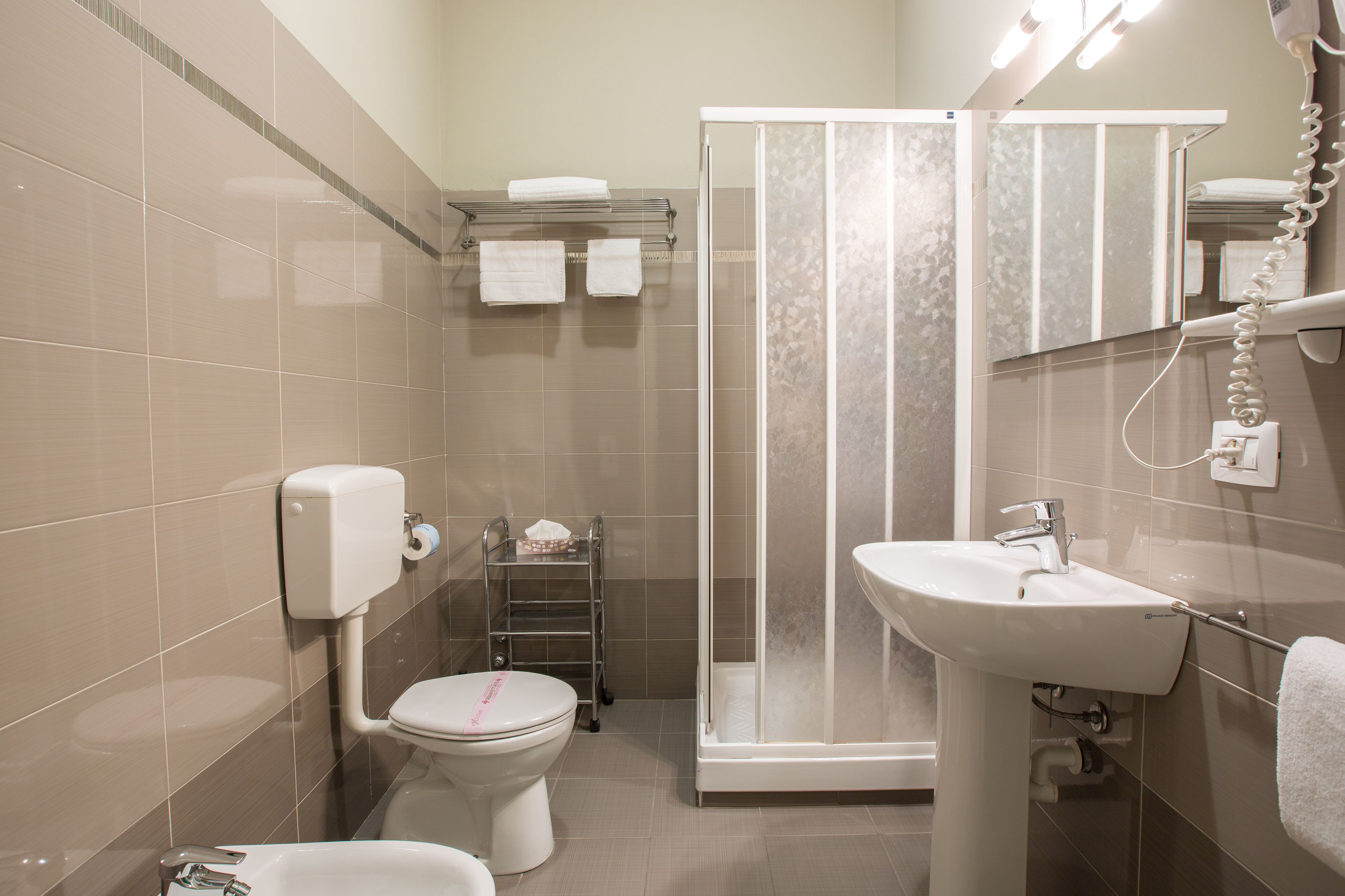 Une salle de bain comprenant des toilettes, un lavabo, une douche avec une porte en verre et un porte-serviettes.