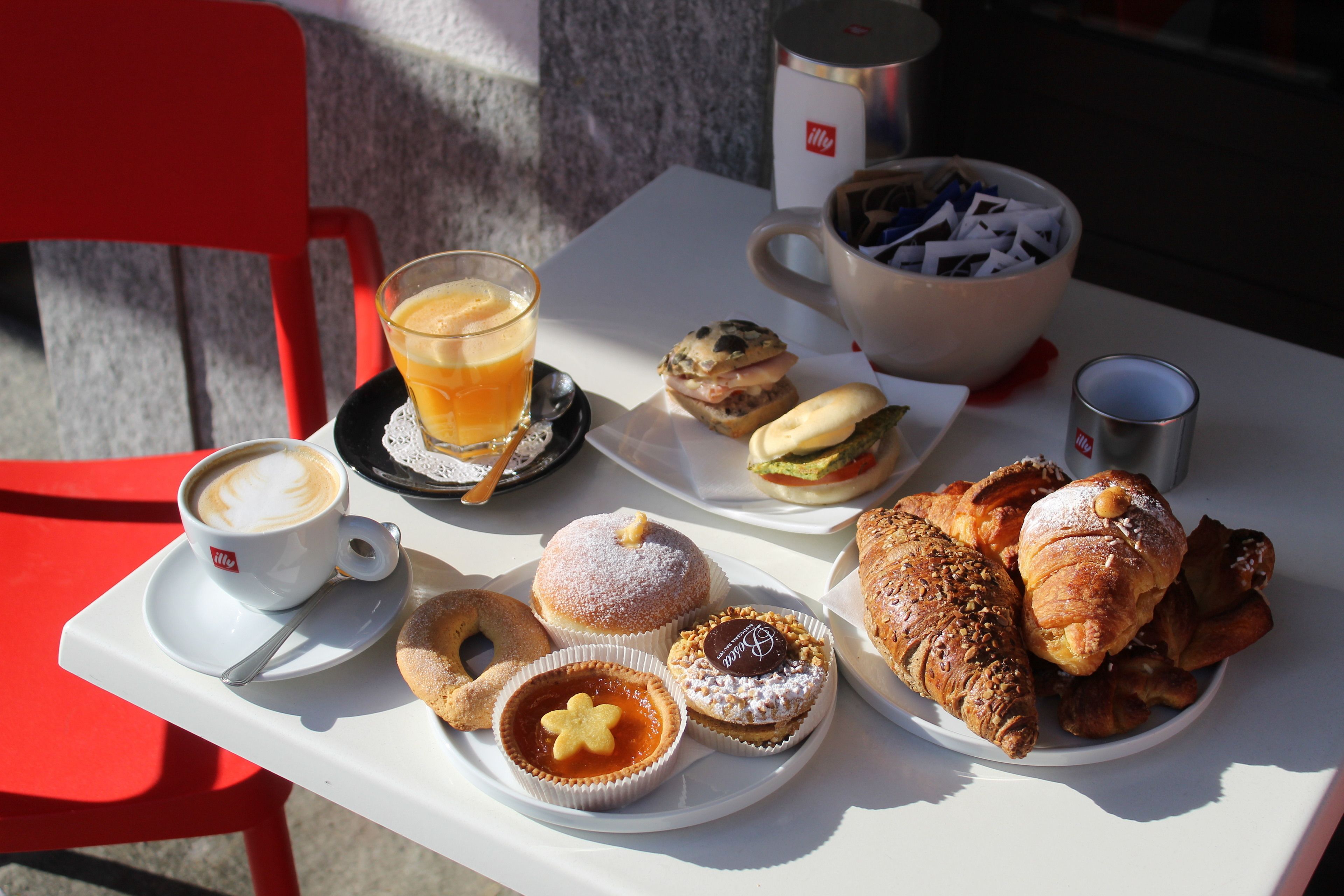 A table with a variety of pastries, a coffee cup, and a glass of orange juice.
