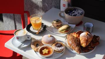 A table with a variety of pastries, a coffee cup, and a glass of orange juice.