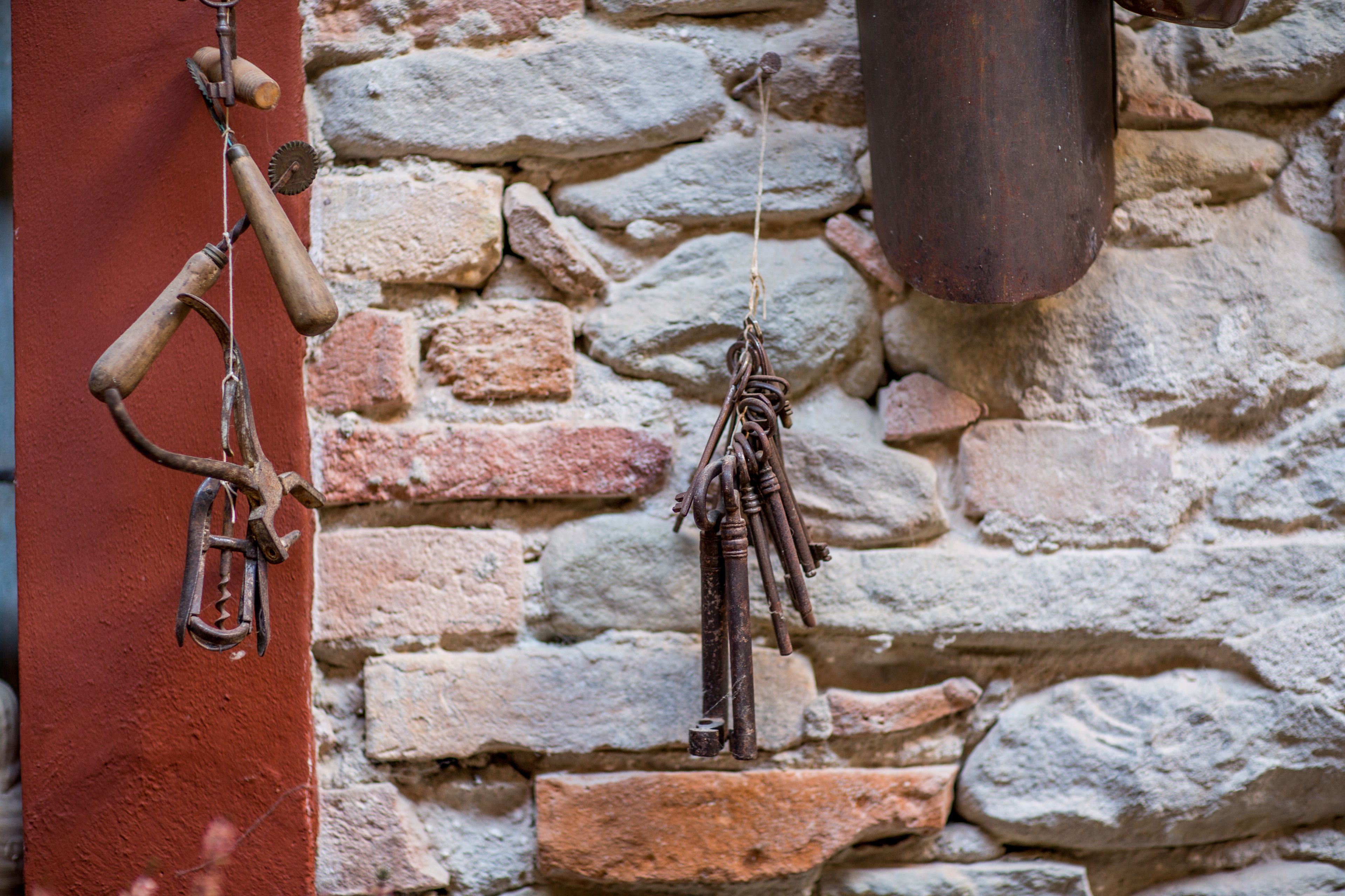 A rustic stone wall with a metal hook and a wooden handle.