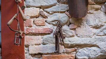 A rustic stone wall with a metal hook and a wooden handle.