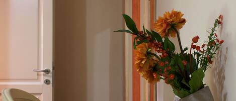 A dining table with a vase of flowers, a chair, and a door in the background.