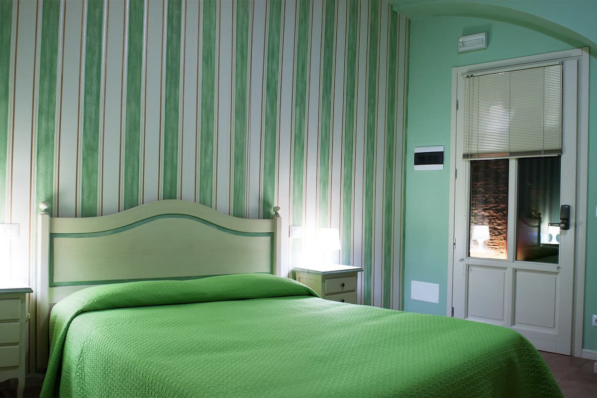 A bedroom with a bed, a nightstand, a dresser, a chair, and a door with a window.