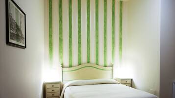 Une chambre à coucher avec un lit, deux tables de chevet, une commode, un tableau encadré au mur et une tête de lit à rayures.