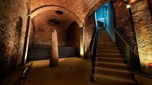 A staircase in a brick-walled building with a wooden column and a metal railing. - Camere Centro Storico (Canelli)