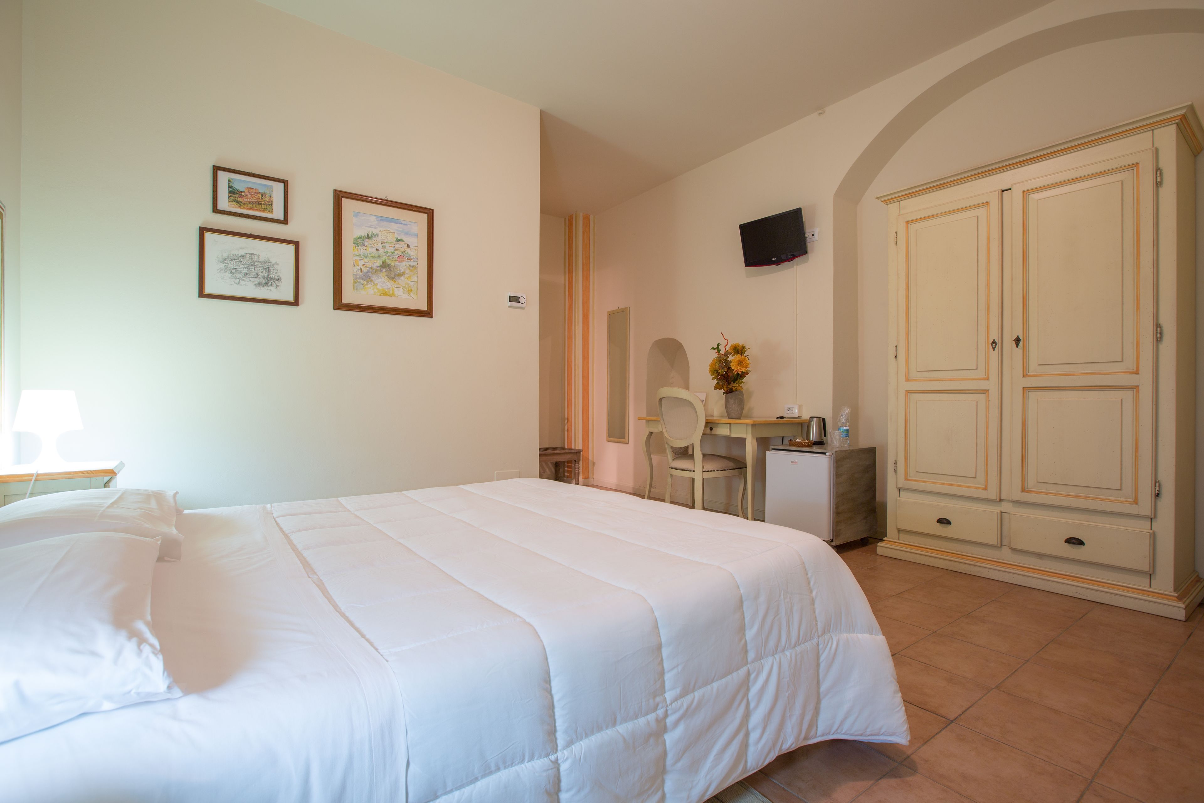 Une chambre d’hôtel équipée d’un lit, d’un bureau, d’une chaise, d’une télévision et d’une armoire.