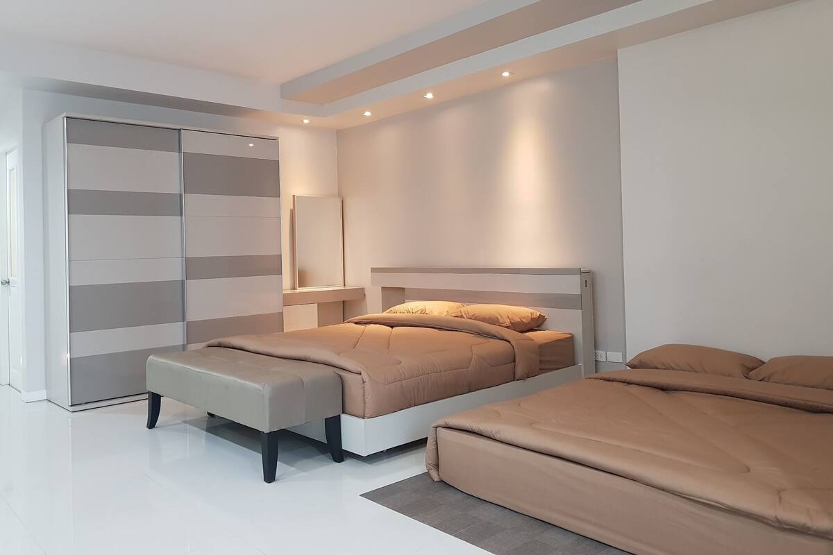 Un dormitorio moderno con cama, banca y armario.
