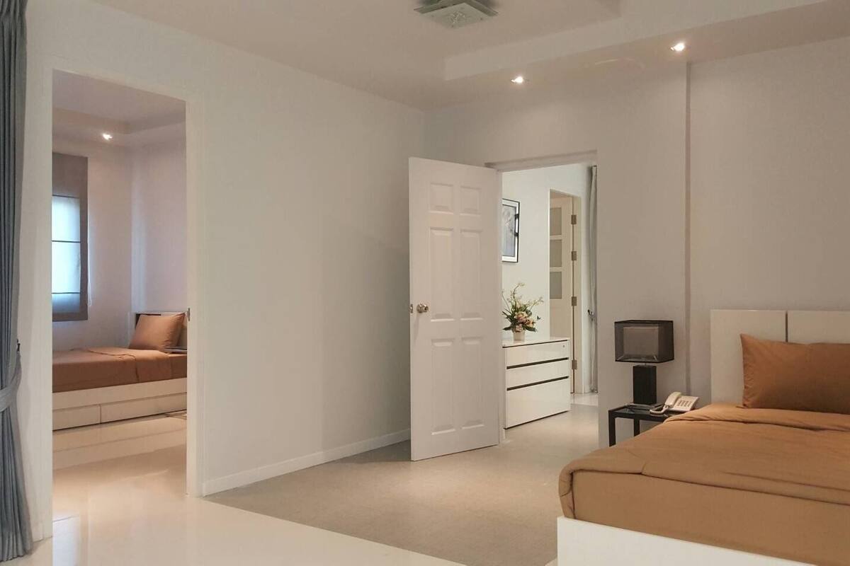 Un dormitorio moderno con cama, televisión y escritorio con cajones.