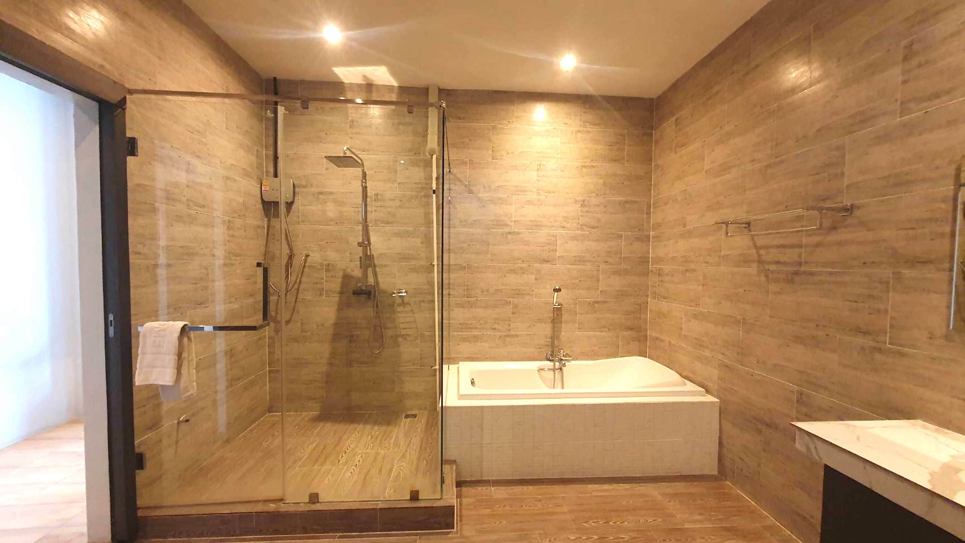 A modern bathroom with a glass-enclosed shower, a freestanding bathtub, and wooden flooring.