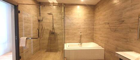 A modern bathroom with a glass-enclosed shower, a freestanding bathtub, and wooden flooring.