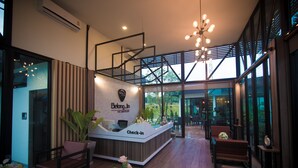 A modern reception area with a check-in desk, seating, and large windows offering a view of the outdoors. - Belong Jin The Dam Hotel & Resort (Ban Ta Khun)