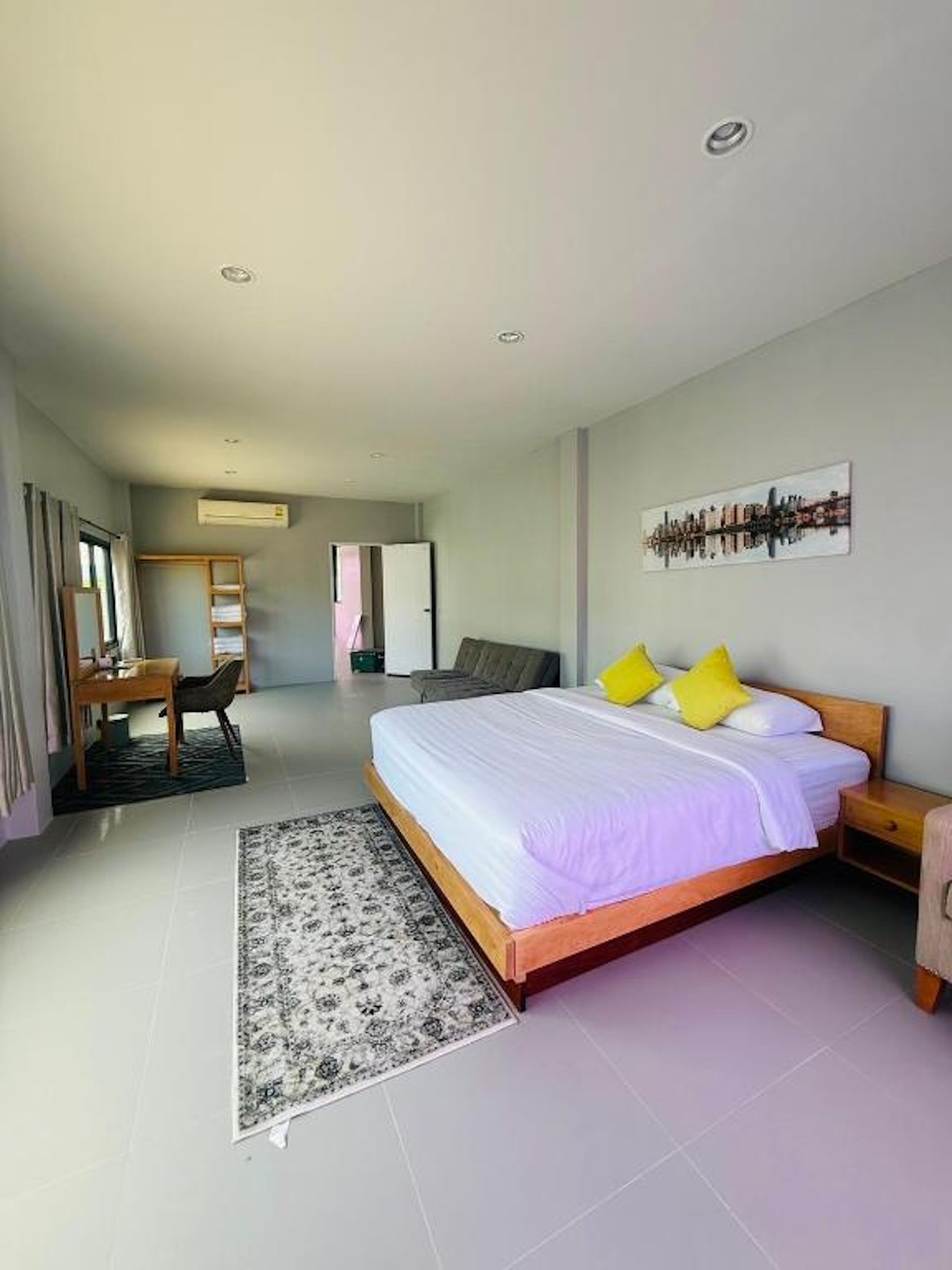 A modern hotel room with a large bed, a desk, a chair, and a small table.