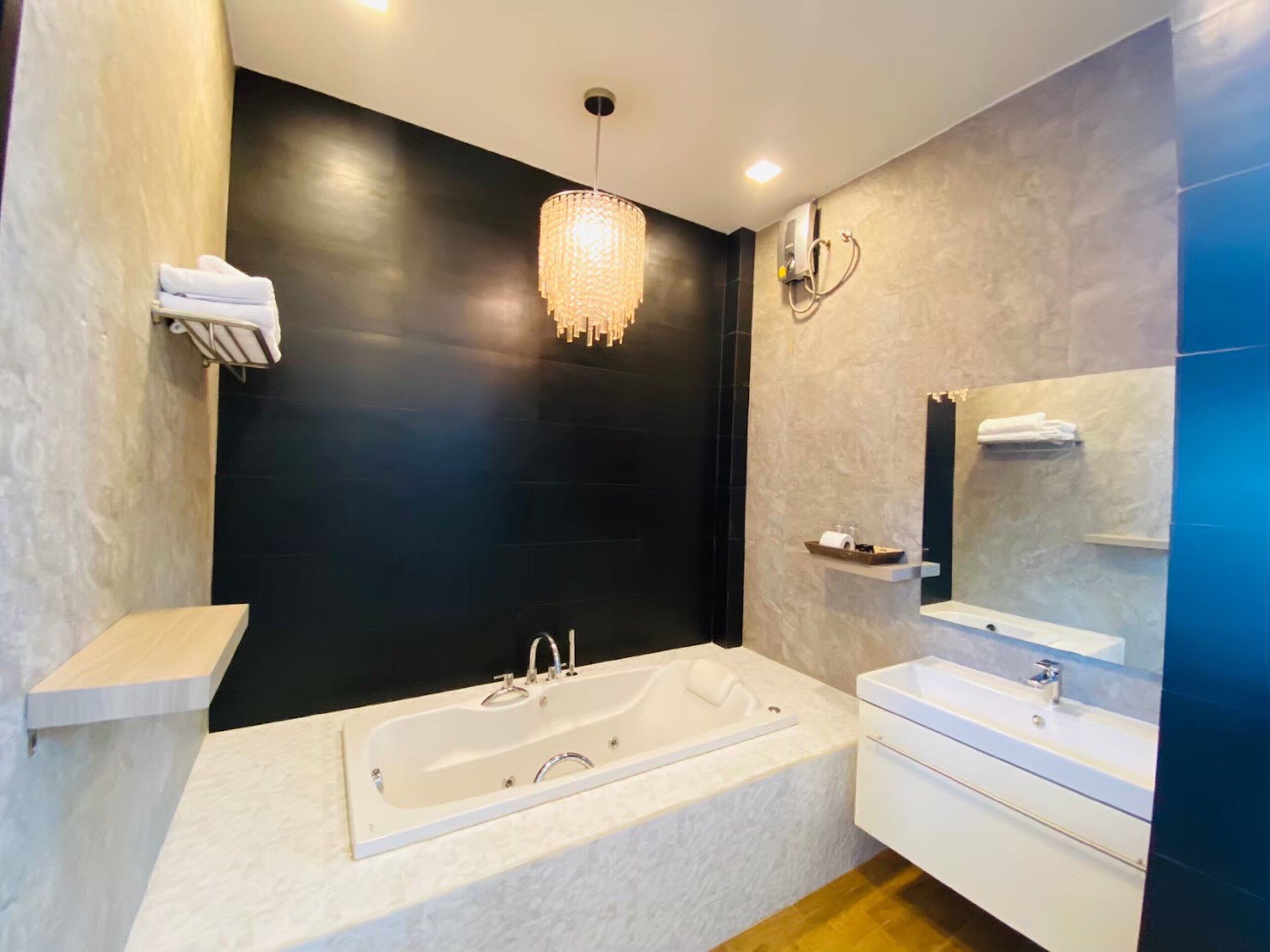 A modern bathroom with a large bathtub, a vanity with a mirror, and a chandelier.