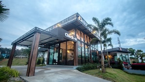 A modern hotel with a glass facade, a check-in area, and a covered outdoor seating area. - Belong Jin The Dam Hotel & Resort (Ban Ta Khun)